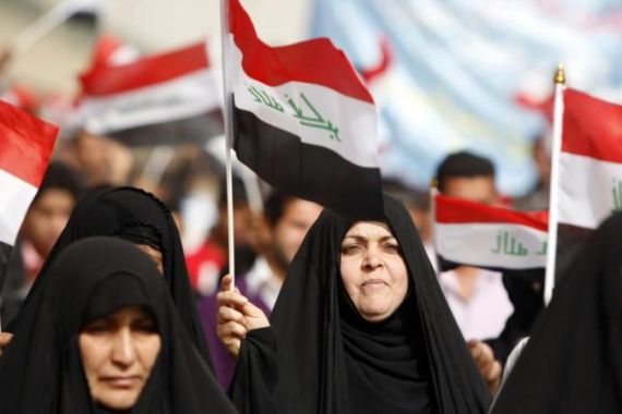 Women supporters wave Iraqi flags at a c