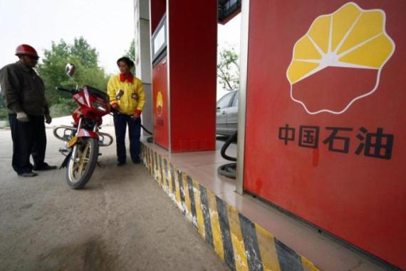 File picture shows a station attendant filling a motorcycle''s petrol tank at a PetroChina gas station in Suining, Sichuan province