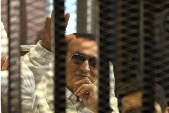 Former Egyptian President Hosni Mubarak waving from behind bars on a stretcher