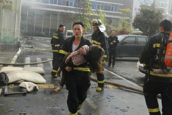 A firefighter carries a girl from the site of a hotel fire in Xiangyang