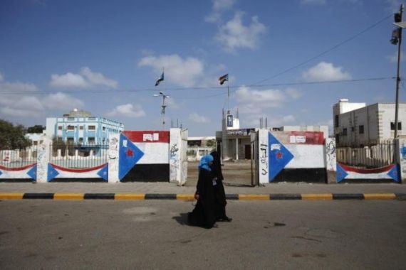Women walk past flags of former South Yemen painted on walls in the southern Yemeni port city of Aden