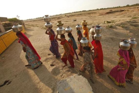 Women carry metal pitchers containing drinking water to their homes at Merta district in Rajasthan