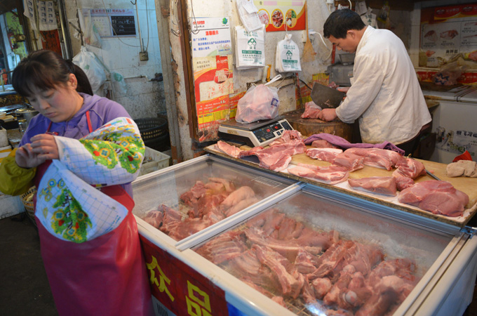 A butcher (R) chops pork at a market in Shanghai