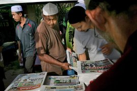 Men look at newspapers in Malaysia