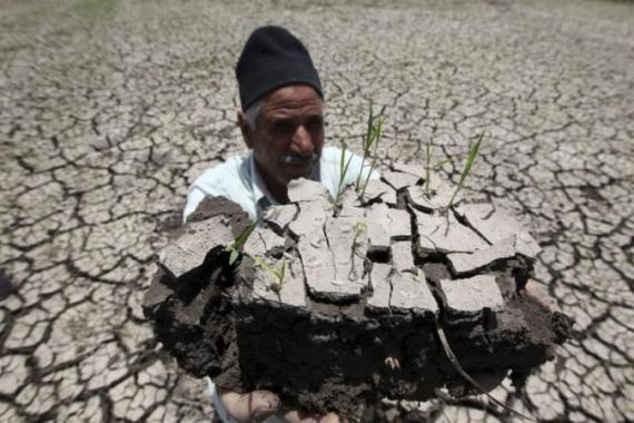 An Egyptian farmer holds a handful of soil to show the dryness of the land due to drought in a farm formerly irrigated by the river Nile, in Al-Dakahlya