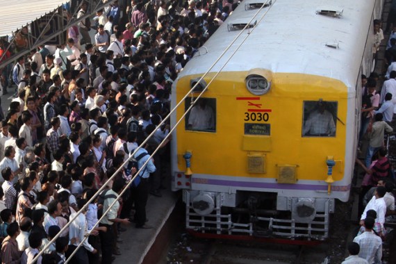 Indian commuters wait on an over-crowded platform to board a local train