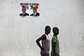 Youths walk past a poster of U.S. President Obama and Senegal''s President Sall before Obama''s visit in Dakar