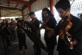 Palestinian students play their instruments during a joint performance with guest musicians at the Qalandiya checkpoint