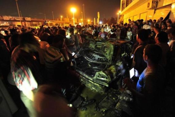 Onlookers gather around the wreckage of a car, which exploded near members of a special forces unit, in Benghazi