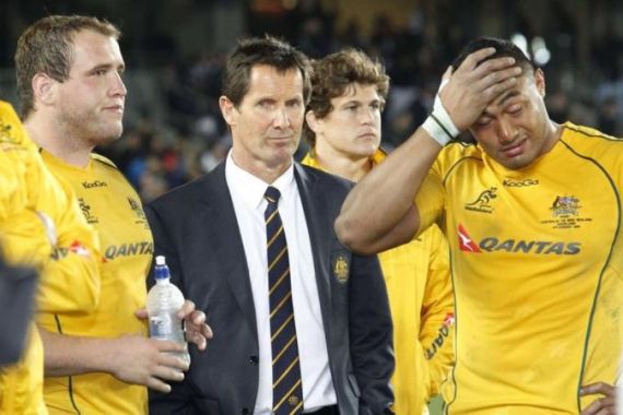 Deans, then-coach of Australia''s Wallabies, reacts as he stands among players after losing a match against New Zealand''s All Blacks in Auckland