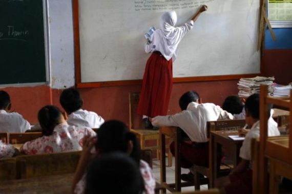 Sofiah stands on a chair as she writes on a whiteboard during class in a school at Sanghiang Tanjung village in Lebak regency, Indonesia''s Banten village