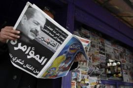 A man reads a local newspaper, displaying a picture of assassinated prominent Tunisian opposition politician Chokri Belaid, at a kiosk in Tunis