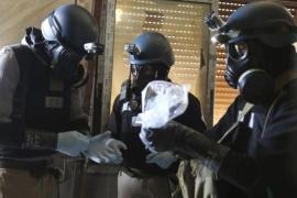 A UN chemical weapons expert holds a plastic bag containing samples from one of the sites of an alleged chemical weapons attack in Ain Tarma Syria