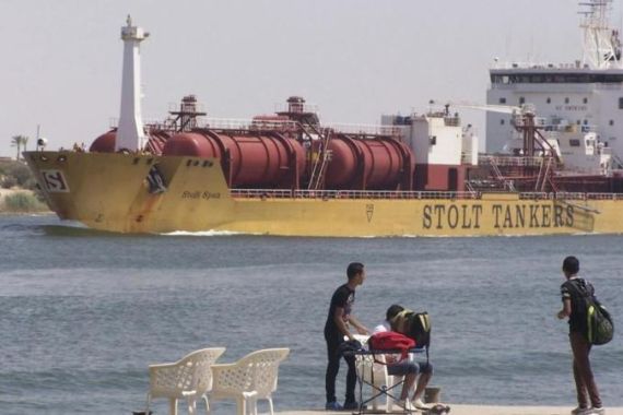 People are seen near a ship crossing the Suez Canal near Ismailia port city