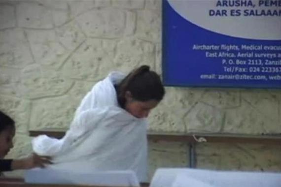 Still image taken from video of one of the two British teenage victims of an acid attack being escorted by an unidentified woman at the airport in Zanzibar