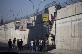 Palestinians without permits to enter Israel during Ramadan use a ladder to climb over the Israeli wall in a bid to attend Friday prayers at Al-Aqsa Mosque