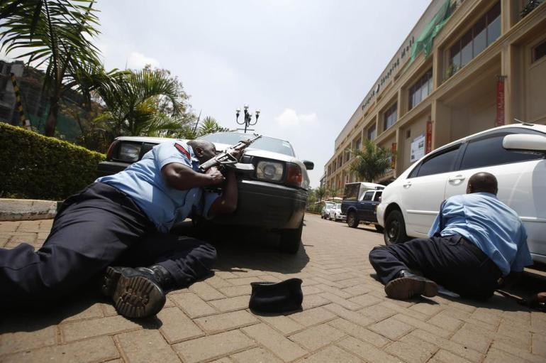 Police take cover outside Westgate shopping centre where gunmen went on a shooting spree in Nairobi