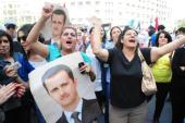Syrian demonstrators shout slogans and wave portraits of Syrian President Bashar al-Assad in support of the president in Damascus on April 28 [AFP]