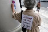 A woman carrying on her back a placard that reads 'Controlling one's life until the end' [AFP]
