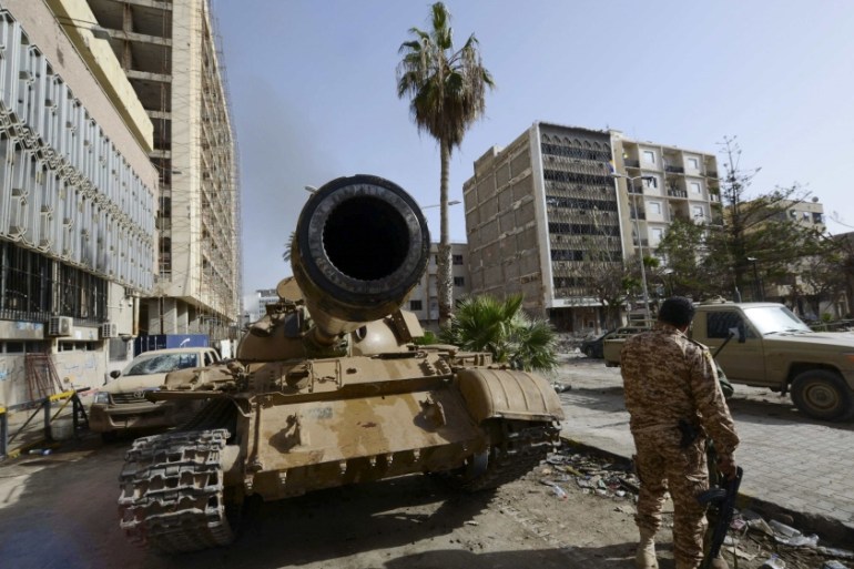 A member of the Libyan pro-government forces, backed by locals, stands near a tank outside the Central Bank, near Benghazi port