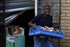 A man looks on as he runs with items from a shop believed to be owned by a foreigner, in Soweto