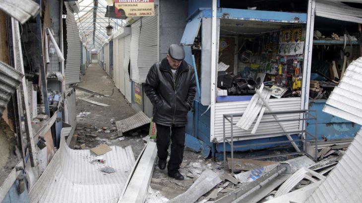 A man walks past a shop which was recently damaged by shelling, at a local market in Donetsk