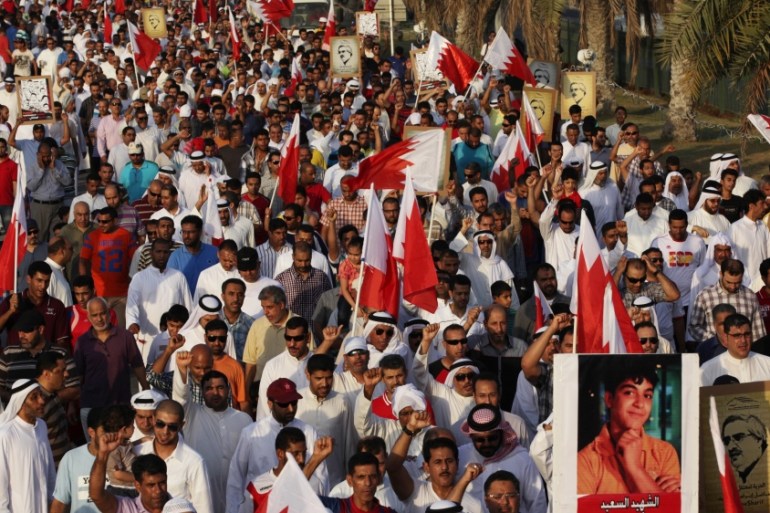Bahrainis carry national flags and posters of protesters killed at a rally in June 2014