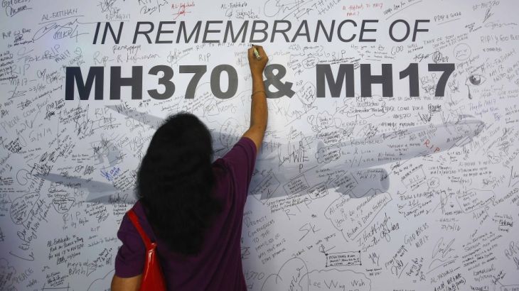 A woman writes a message on a dedication board for victims of the downed Malaysia Airlines Flight MH17 airliner and the missing Flight MH370, in Subang Jaya