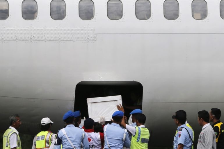 Indonesia soldiers and rescue personnel put a coffin of a passenger of AirAsia Flight QZ8501 into the cargo compartment of a Trigana airplane at Iskandar airbase in Pangkalan Bun