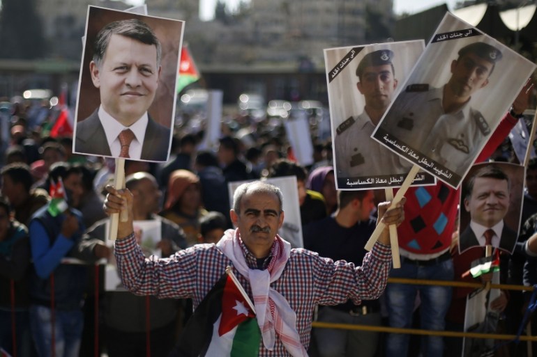 Jordanian protesters hold up pictures of Jordanian King Abdullah in Amman
