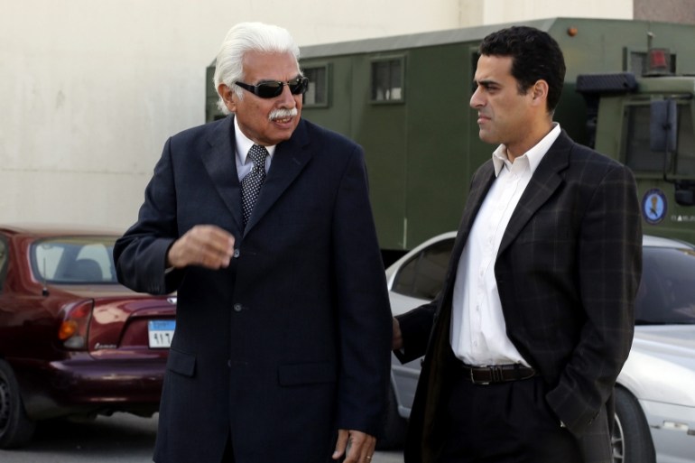Former Egyptian Prime Minister Ahmed Nazif walks with his son outside of a court after his trial was delayed, in the outskirts of Cairo