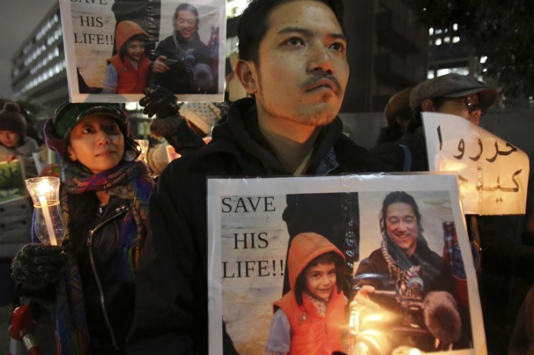 Protesters holding signs bearing a photo of Kenji Goto