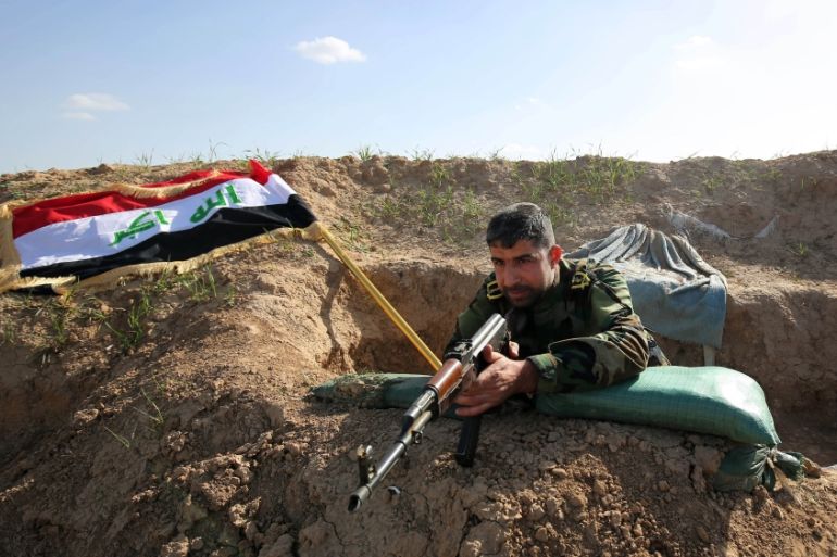 A Shia militia fighter aims his weapon on the frontline just outside the city of Kirkuk [AP]