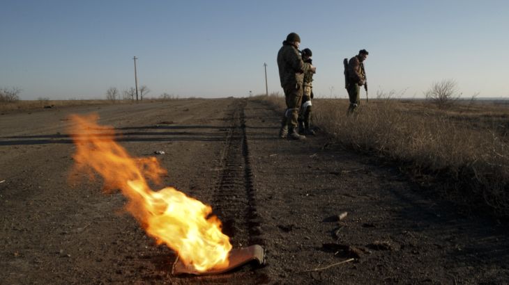 Russia-backed separatists search a road littered with destroyed Ukrainian army vehicles outside Debaltseve, Ukraine [AP]