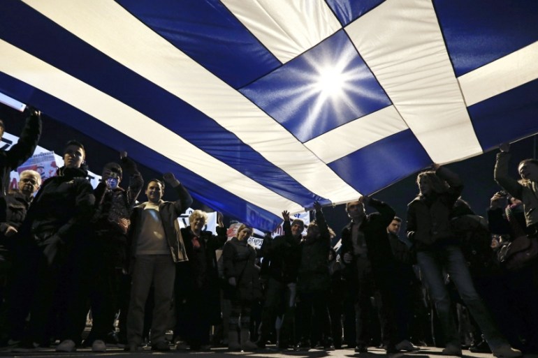 Protesters hold a giant Greek national flag during an anti-austerity and pro-government demonstration in front of the parliament in Athens
