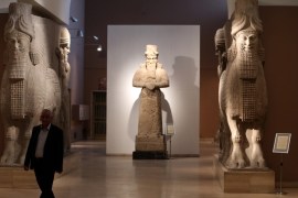 A man at Iraq''s National Museum in Baghdad walks past two ancient Assyrian human-headed winged bull statues [AP]