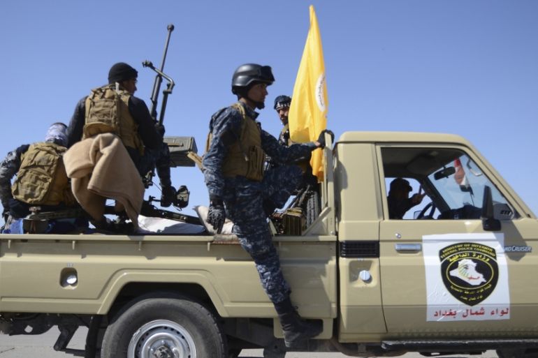 Members of Iraqi security forces ride on a vehicle as they make their way from Samarra to the outskirts of Tikrit