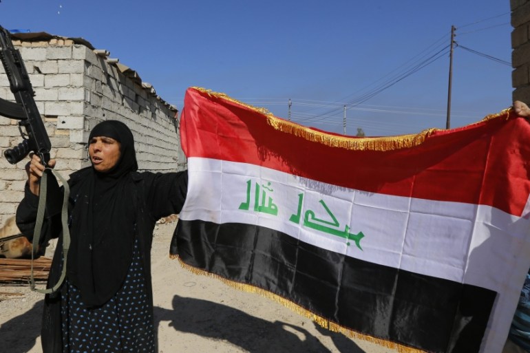 A woman with a weapon and the Iraqi flag in the town of al-Alam [REUTERS]