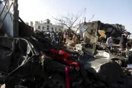 People gather at the site of an air strike at a residential area near Sanaa Airport