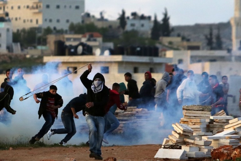 A Palestinian demonstrator throws a rock towards Israeli security forces during clashes following a protest against the expansion of settlements in a West Bank village, north of Ramallah [
