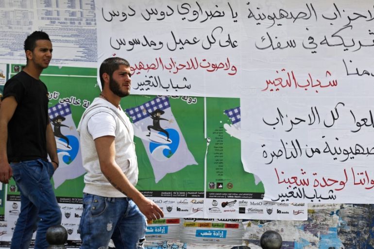 Arab Israeli men pass posters handwritten in Arabic calling Arabs not to vote for the Zionist parties in the Arab Israeli city of Nazareth, Israel [EPA]