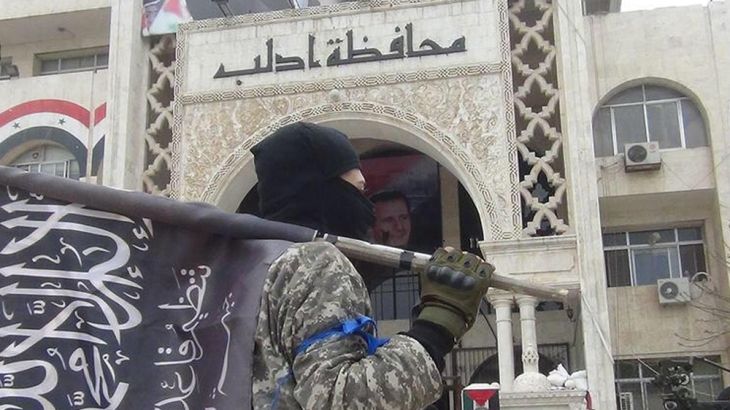 Nusra Front fighter standing in front of a government building in Idlib, Syria