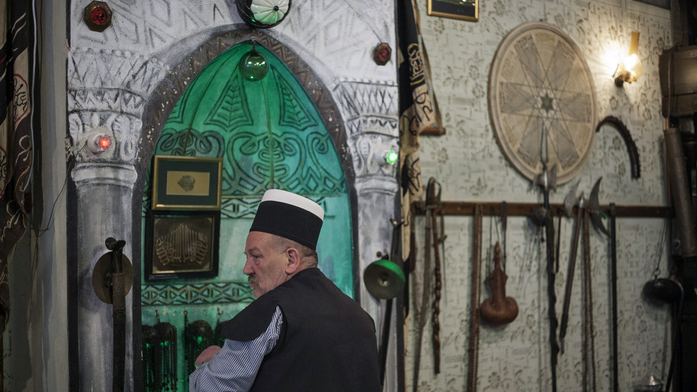 A member of the Sufi sect prepares the zarfs at the mimber before starting the Nowruz ritual [Ferdi Limani/Al Jazeera]