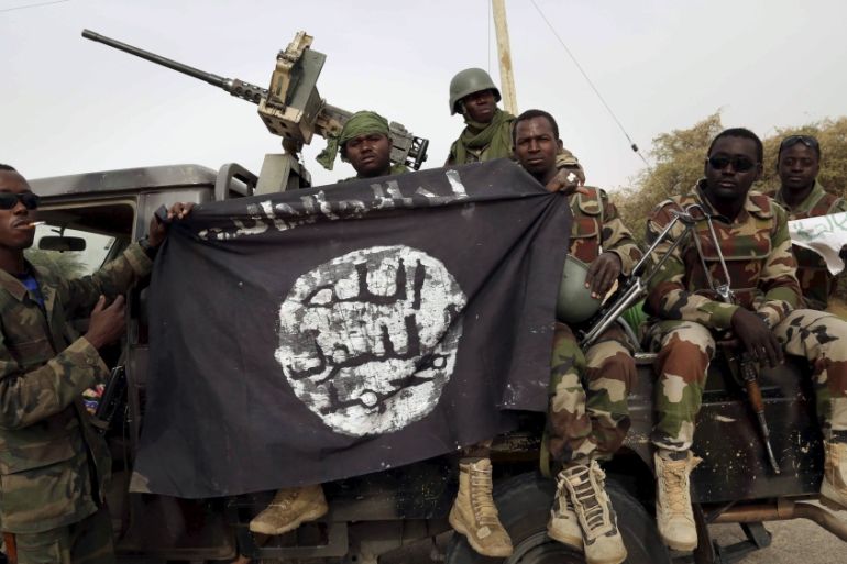 Nigerien soldiers hold up a Boko Haram flag that they had seized in the recently retaken town of Damasak, Nigeria