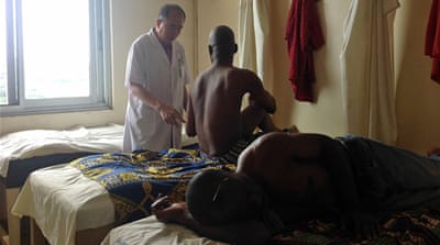 Dr Zhang Mojiang speaks with a patient during a treatment session [Abena Agyeman-Fisher/Al Jazeera]