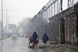 Burqa-clad Afghan women and a child walk during a snow storm in Kabul, Afghanistan [AP]