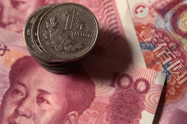 File photo illustration of Chinese one yuan coins being placed on 100 yuan banknotes in Beijing