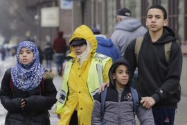 A crossing guard assists three Muslim school children at the end of a school day in the Brooklyn borough of New York [AP]