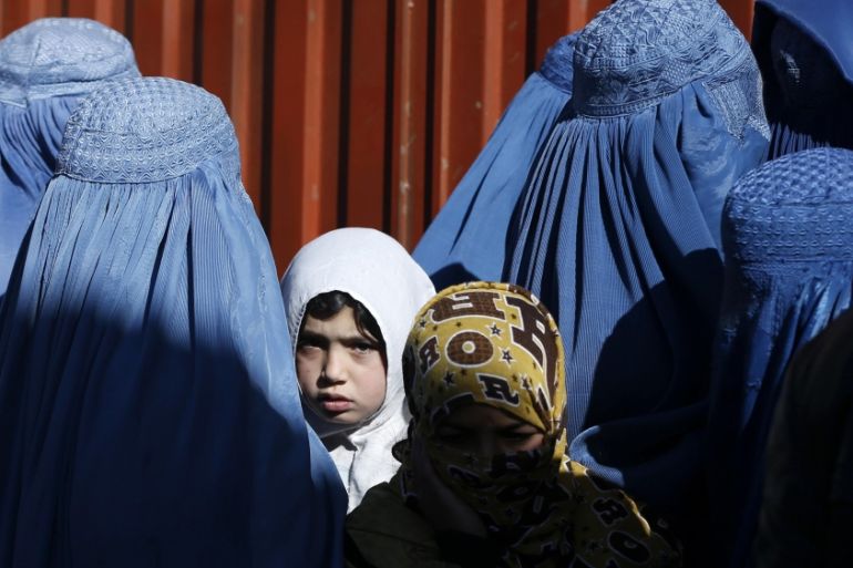 A girl looks on among Afghan women lining up to receive winter relief assistance donated by the United Nations High Commissioner for Refugees (UNHCR) in Kabul [Reuters]