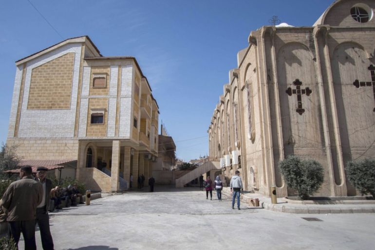Displaced Assyrians, who fled from the villages around Tel Tamr, sit outside the Assyrian Church in al-Hasaka city